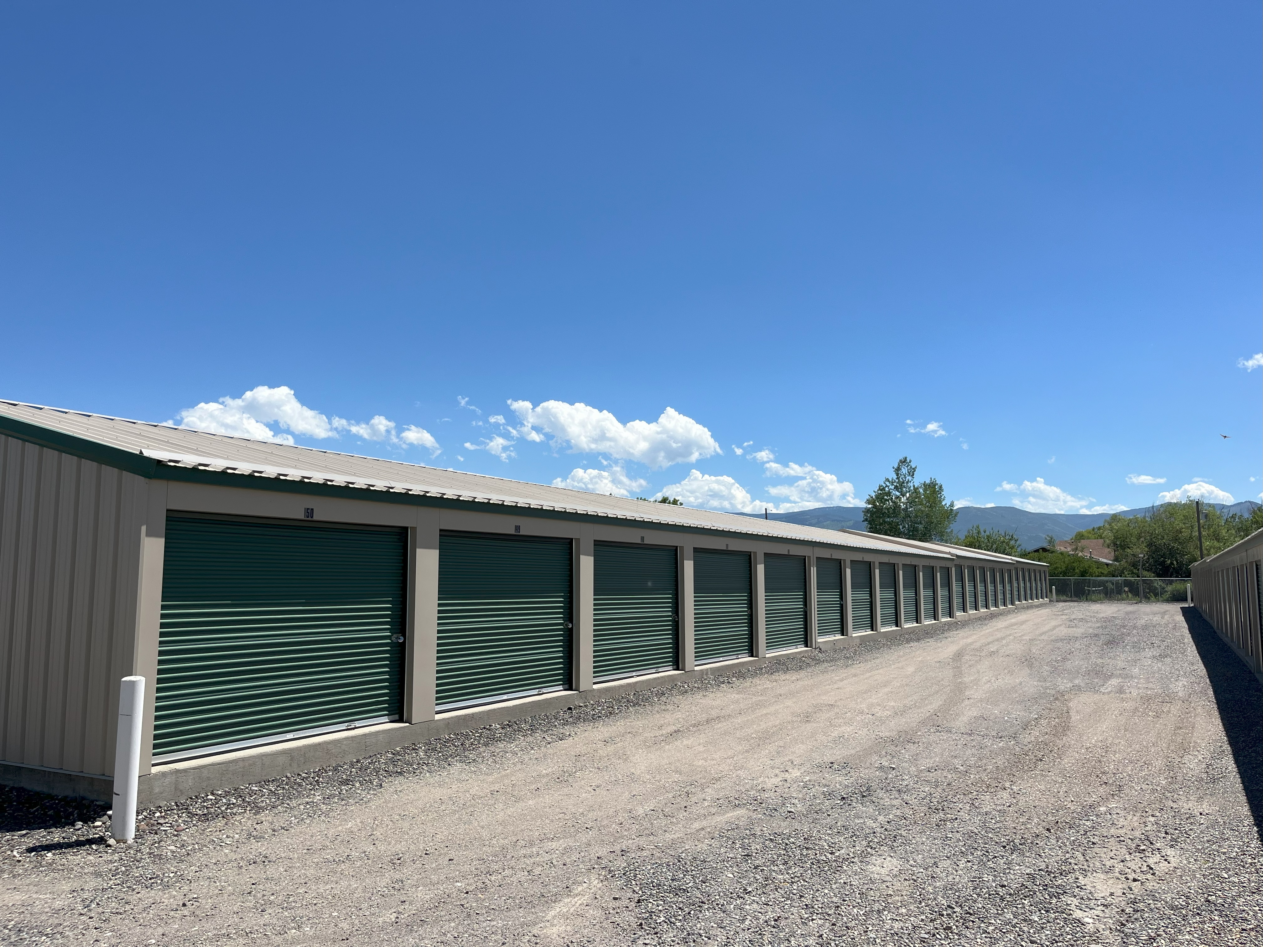 Long row of storage units - tan buildings, green doors at Alpine Storage MT
